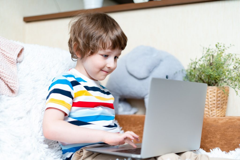 Online school at home. Kid study with laptop, playing video games
